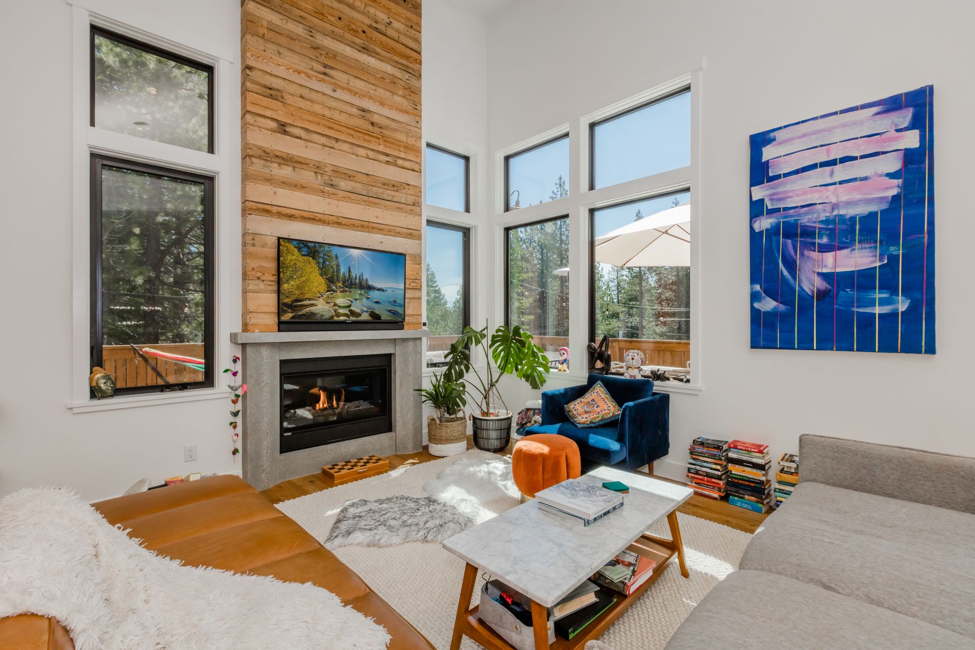 Spacious and sunny living room in a Truckee home with modern décor, featuring a stone fireplace, large windows.